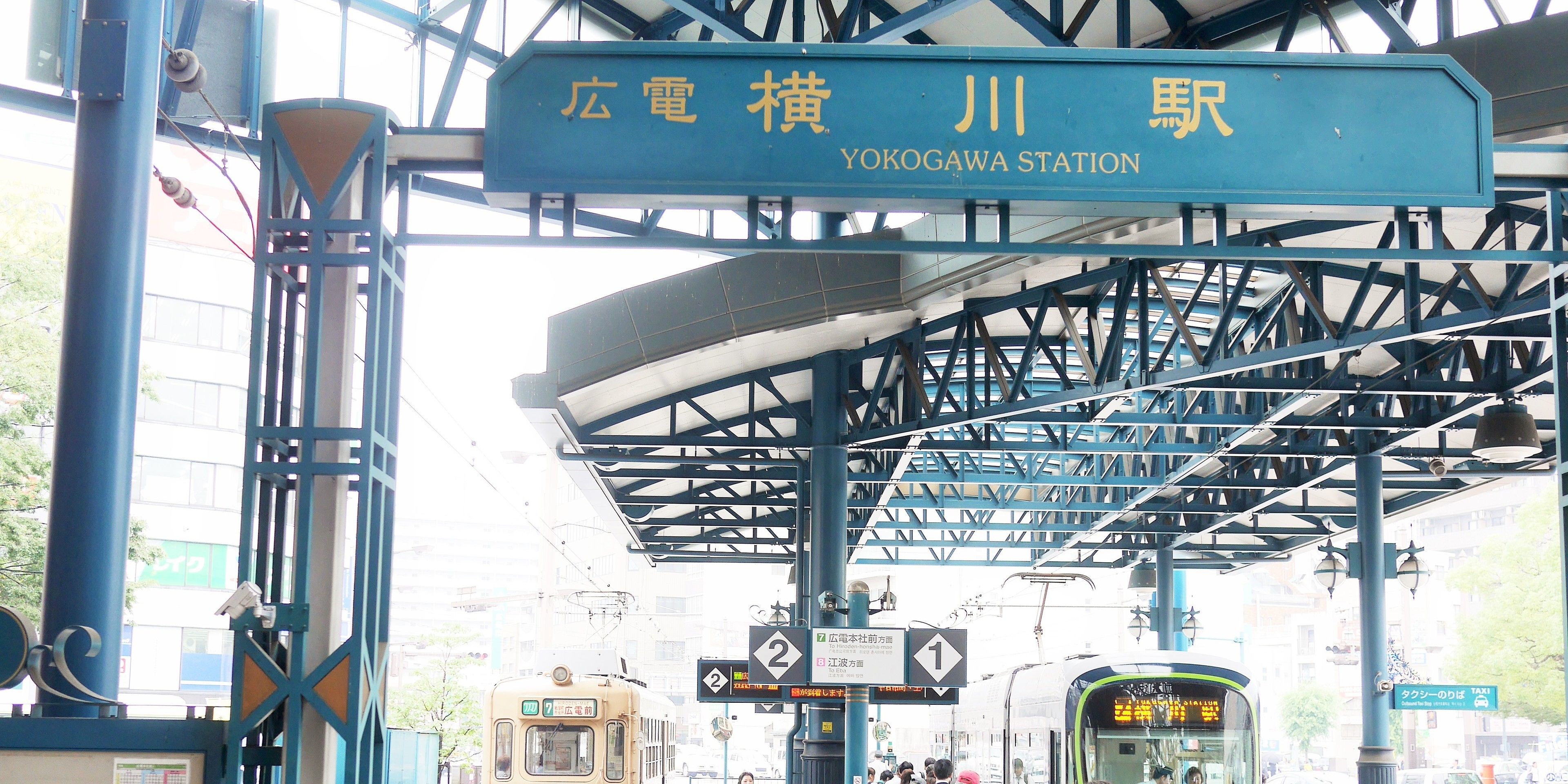 Yokogawa Station with a blue signboard, a covered waiting area, and a train platform.