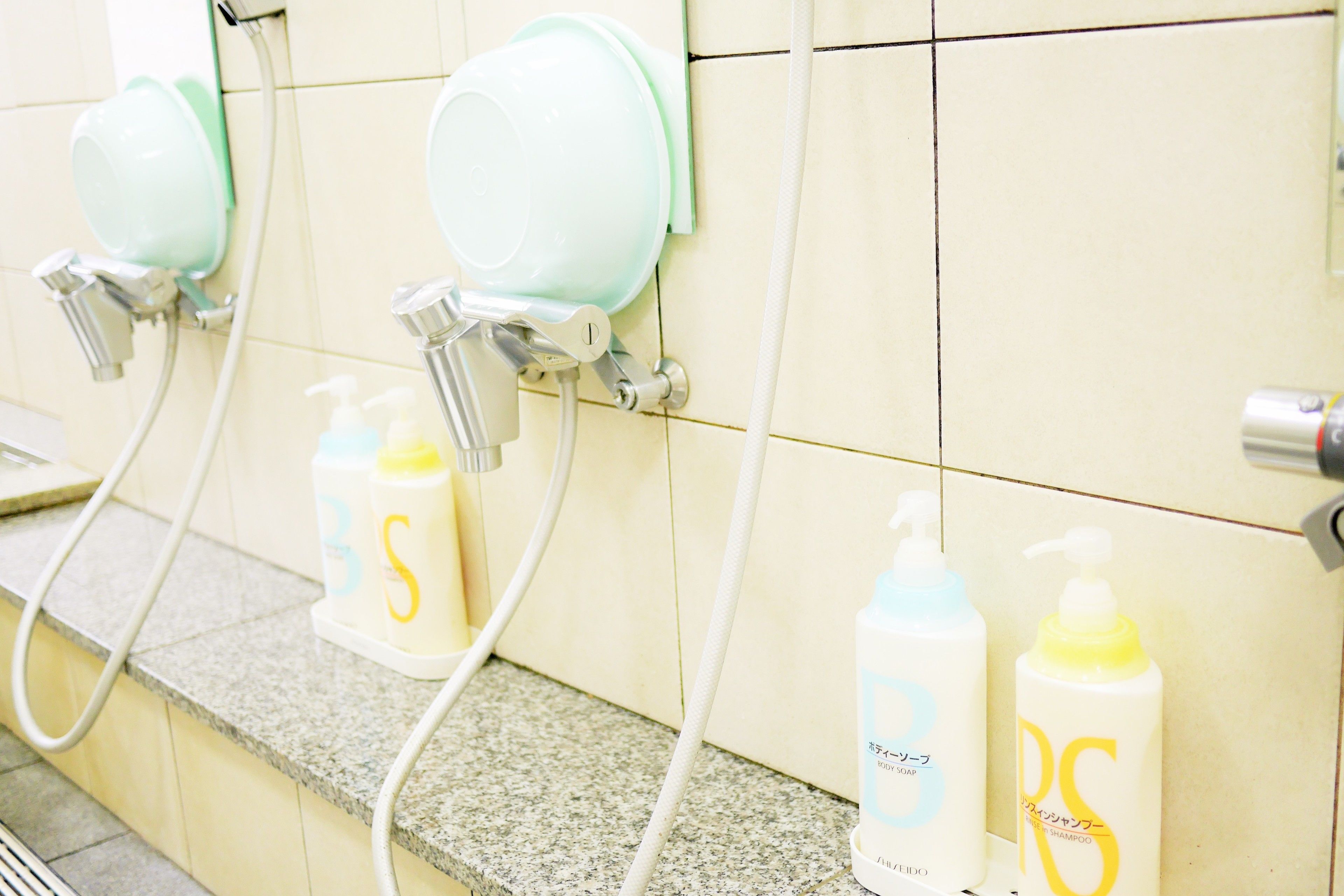 Un baño con varios lavamanos, cada uno con dispensador de jabón y espejo.
