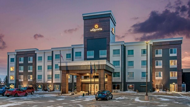 A multi-story hotel with a prominent 'La Quinta' sign on the facade, featuring a modern architectural design with a mix of brick and glass elements. - La Quinta Inn & Suites by Wyndham Bismarck (Bismarck)