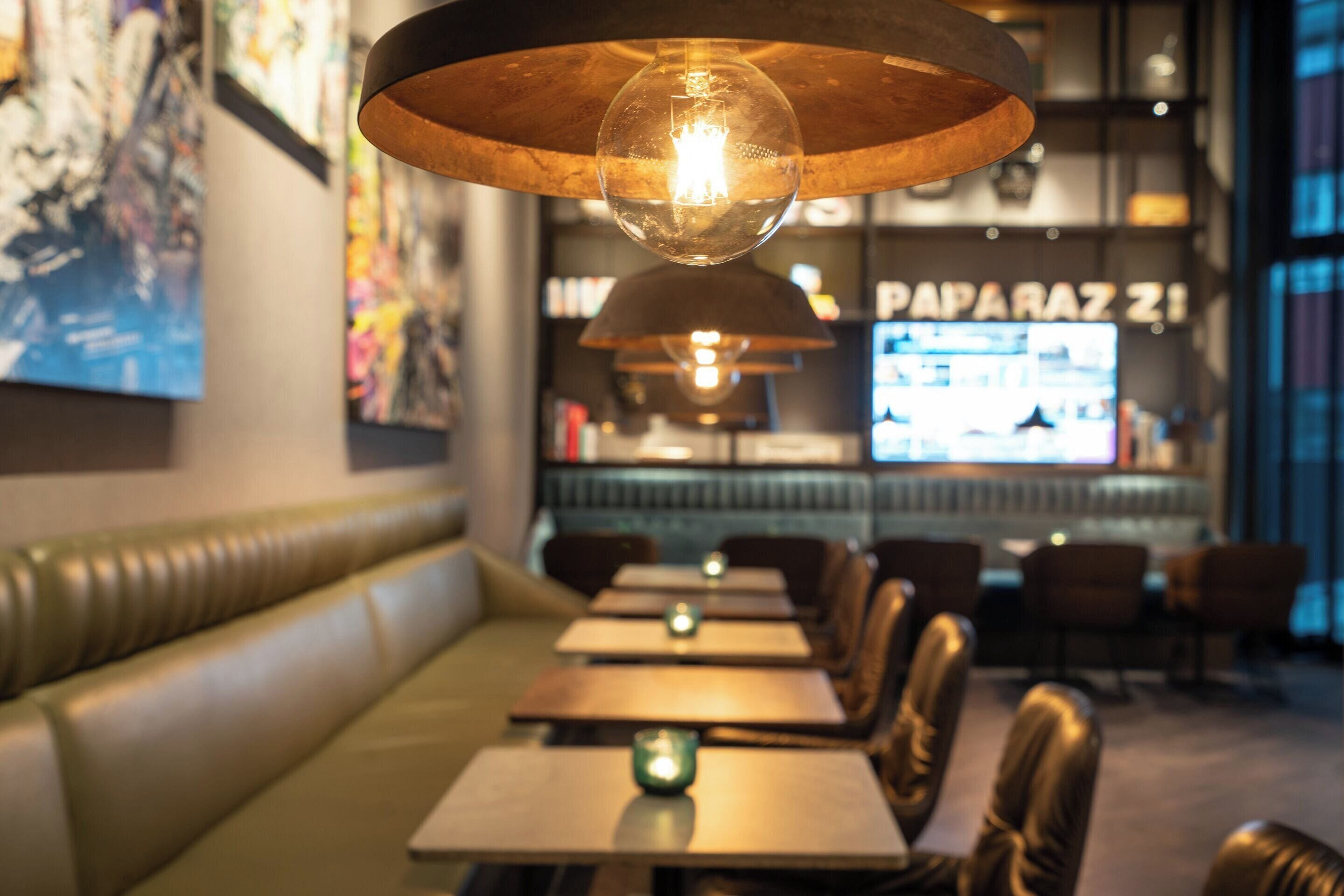 Interior de restaurante con cabinas de cuero, mesas de madera e iluminación colgante.