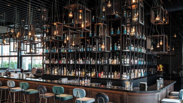 A bar area with multiple shelves of liquor bottles, hanging light fixtures, and bar stools. - Motel One Berlin-Spittelmarkt (Berlin)
