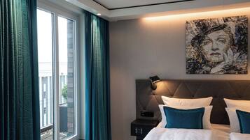 Ein Hotelzimmer mit einem großen Bett, einem Kopfteil, einem Nachttisch mit Lampe und einem an der Wand hängenden Kunstwerk.