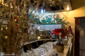 Un espace bar avec un comptoir, des étagères remplies de bouteilles et un sapin de Noël.