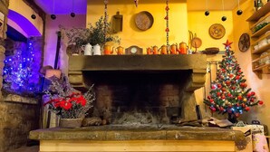 A fireplace with a clock above it, surrounded by various decorative items and a Christmas tree.