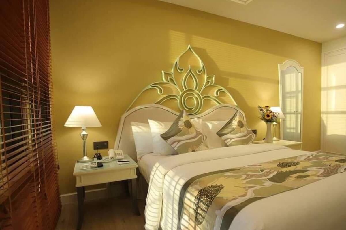 Een hotelkamer met een bed, nachtkastje, lamp en een decoratief wandobject.