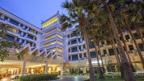 A multi-story hotel with a prominent 'HIMAWARI' sign, featuring a modern architectural design with balconies and a well-maintained garden with palm trees.