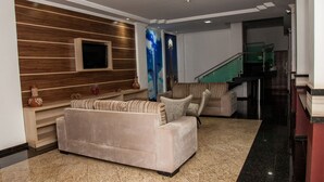 A modern living room with a sofa, a flat-screen TV, decorative items, and a staircase.