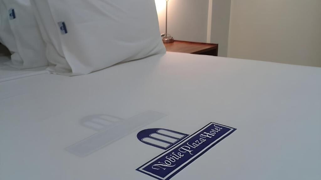Una habitación de hotel con una cama, una mesita de noche y una lámpara.