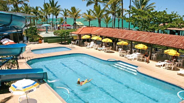 Ein Schwimmbad mit Wasserrutsche, Liegestühlen und Sonnenschirmen.