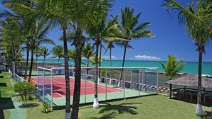 Ein Tennisplatz, umgeben von Palmen, mit Blick auf den Ozean.