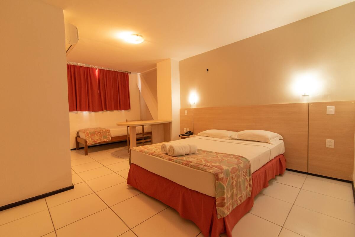 Una habitación de hotel con una cama, un escritorio y una silla.
