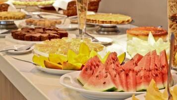 A buffet with various food items including watermelon slices, yellow fruit, and desserts.