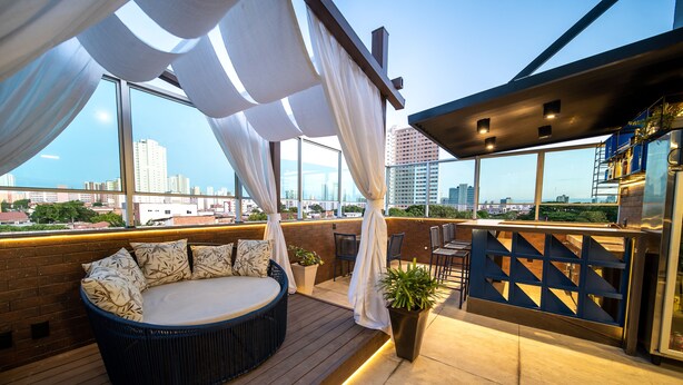 Une terrasse sur le toit avec un espace salon circulaire, un pot de fleurs et une vue sur le panorama urbain.