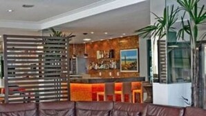 Un intérieur moderne avec un canapé en cuir, un coin bar agrémenté d’un mur en briques et une grande fenêtre.