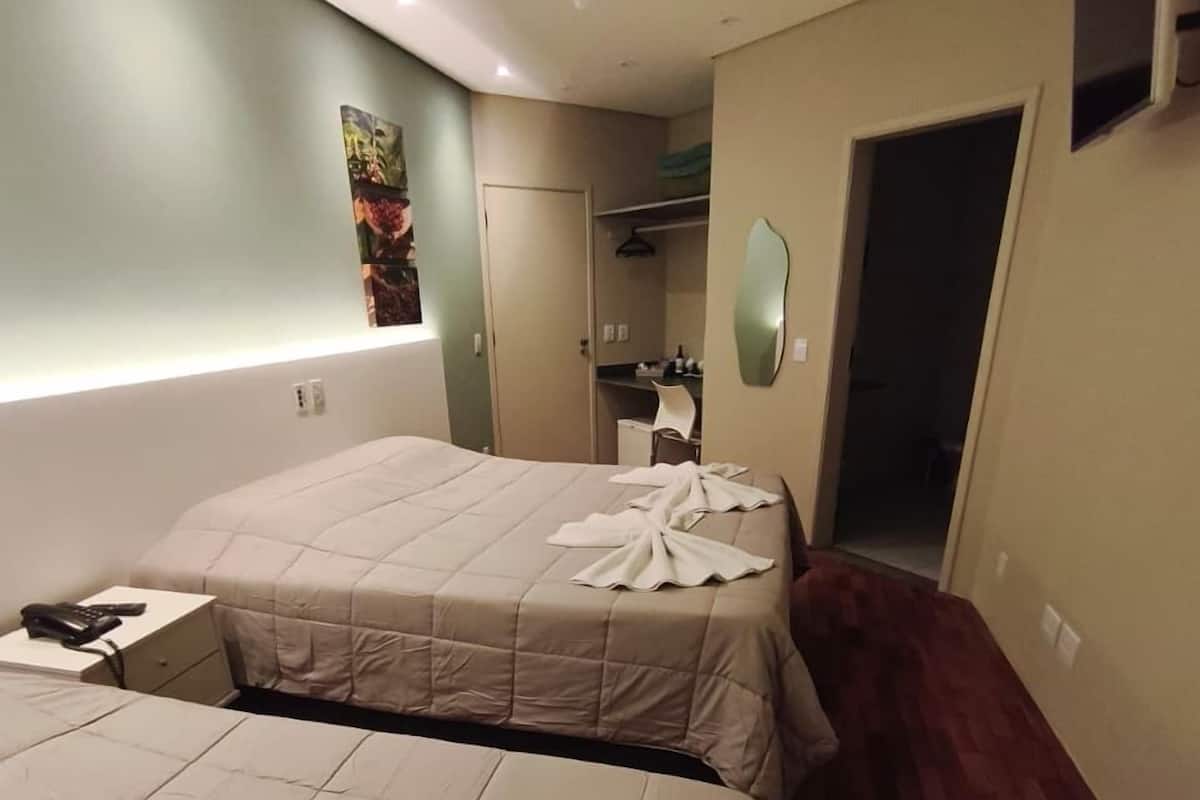 Ein Hotelzimmer mit zwei Betten, einem Deckenventilator, einem Schreibtisch mit Telefon, einem Spiegel und einer Tür zu einem Badezimmer.