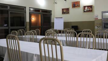 Un salón de conferencias con mesas y sillas, una pizarra y obras de arte en las paredes.