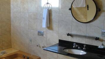 A bathroom with a wooden bathtub, a black sink with a mirror above it, and a towel hanging on a rack.