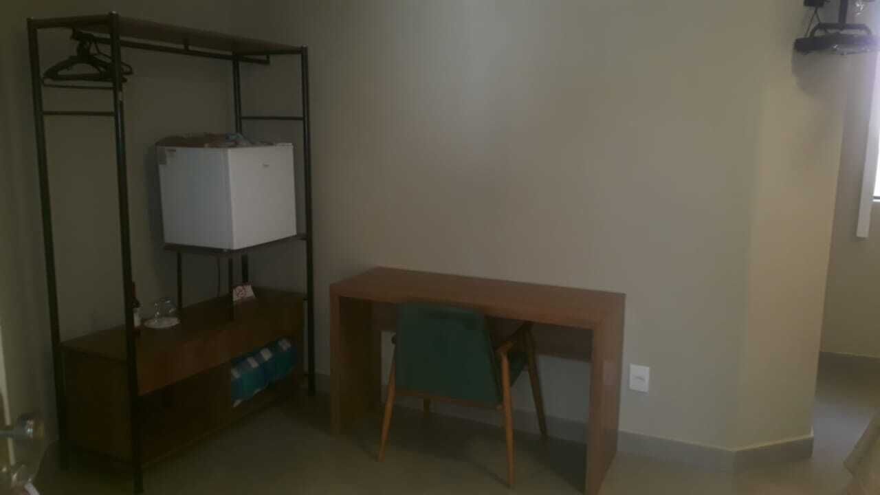 A room with a wooden desk, a metal shelving unit, and a green chair.