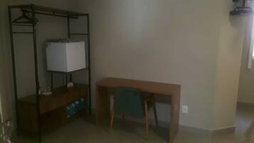 A room with a wooden desk, a metal shelving unit, and a green chair.