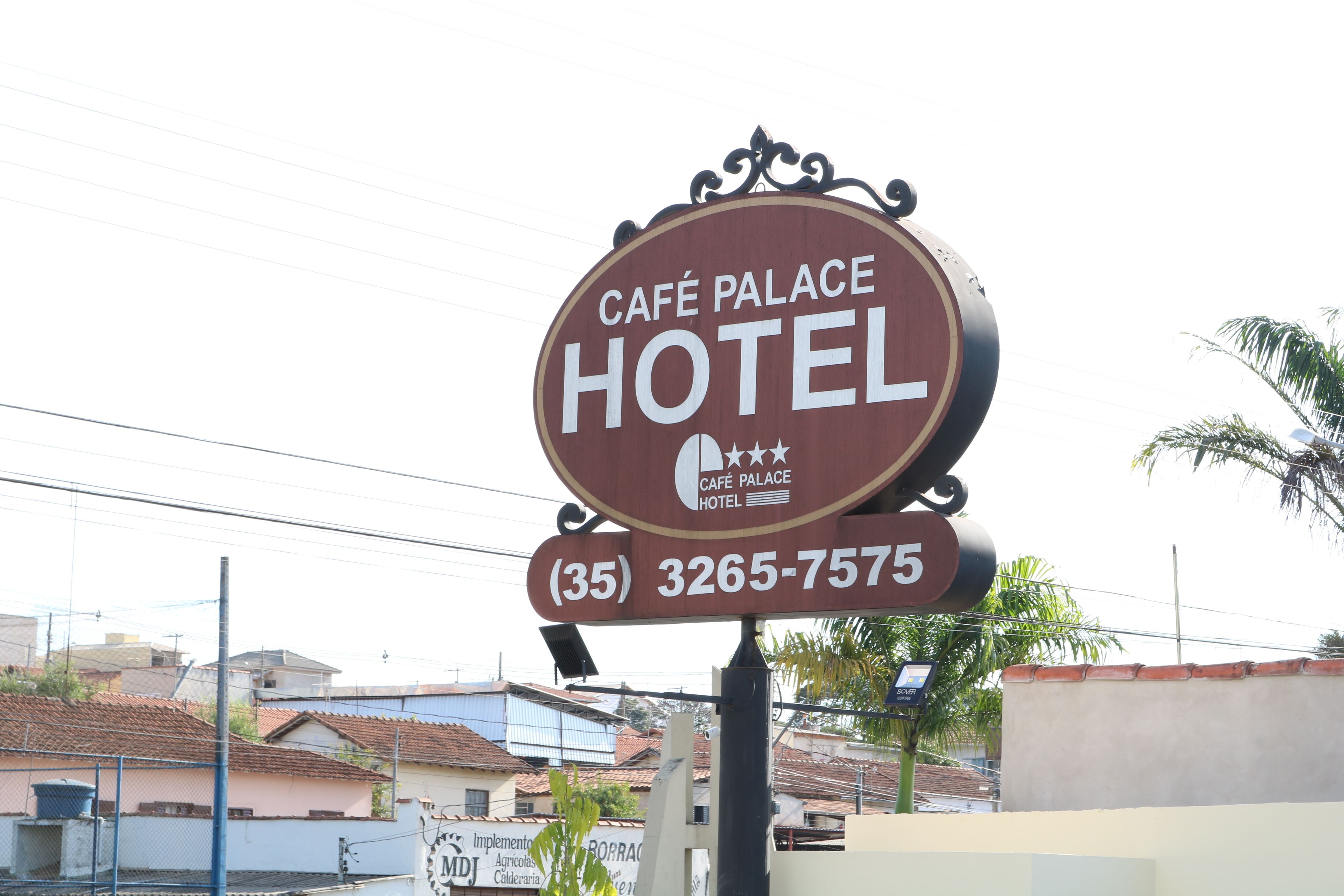 A sign for Café Palace Hotel with a phone number (35) 3265-7575.