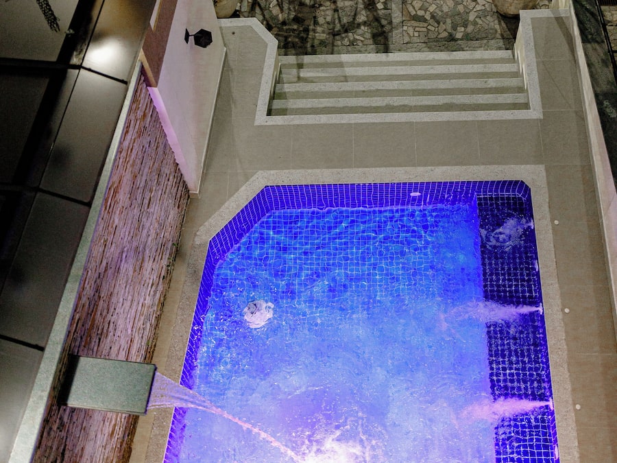 A rooftop pool with a blue mosaic design, surrounded by outdoor seating and potted plants.