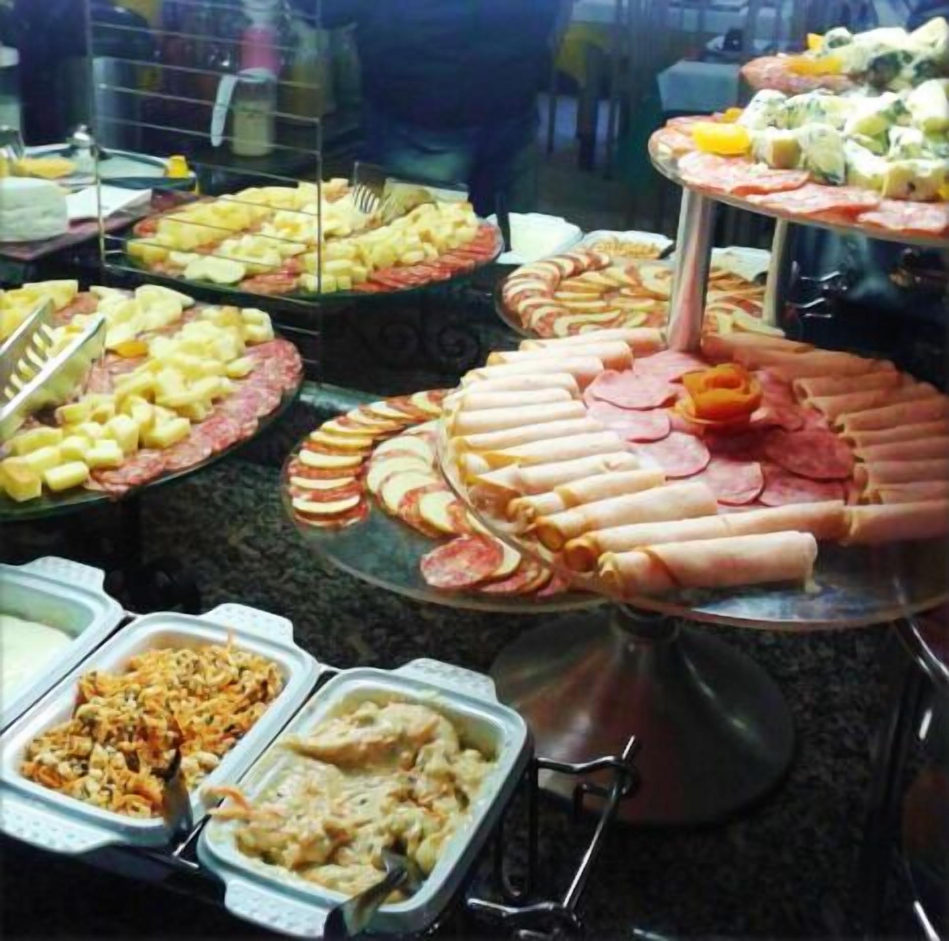 Un buffet proposant une variété de plats, notamment des viandes en tranches, des fruits et des salades.