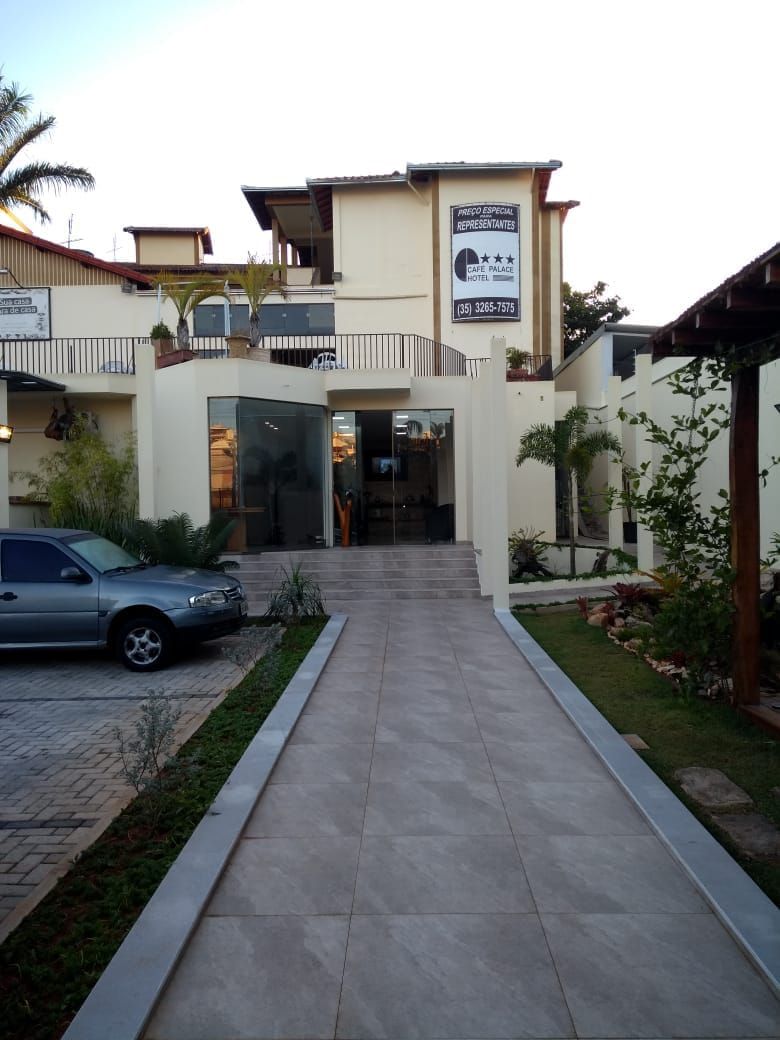 Entrada de hotel com estacionamento pavimentado, um carro estacionado e placa indicando tarifa especial para representantes.