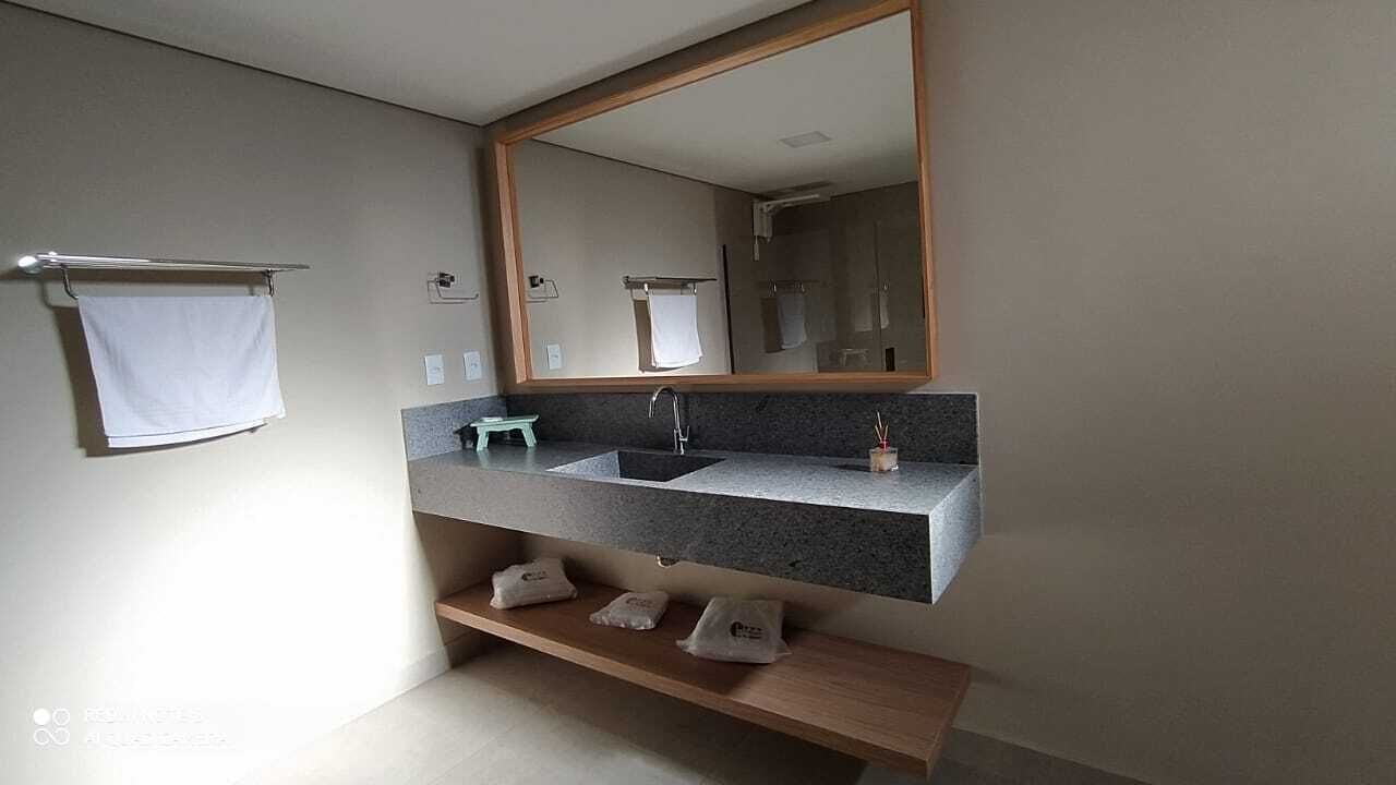A modern bathroom with a granite countertop sink, a large mirror, and a towel rack.