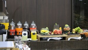 Un buffet proposant une variété de plats et de boissons, notamment des fruits, des jus et un assortiment de fromages.