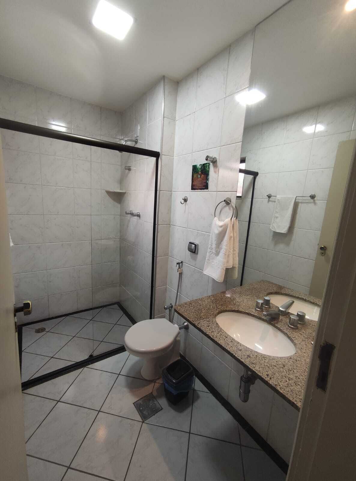 A bathroom with a shower, toilet, sink, and towel rack.