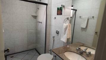 A bathroom with a shower, toilet, sink, and towel rack.