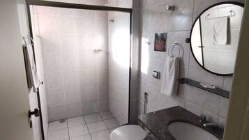 A modern bathroom with a shower, toilet, sink, and a large mirror.
