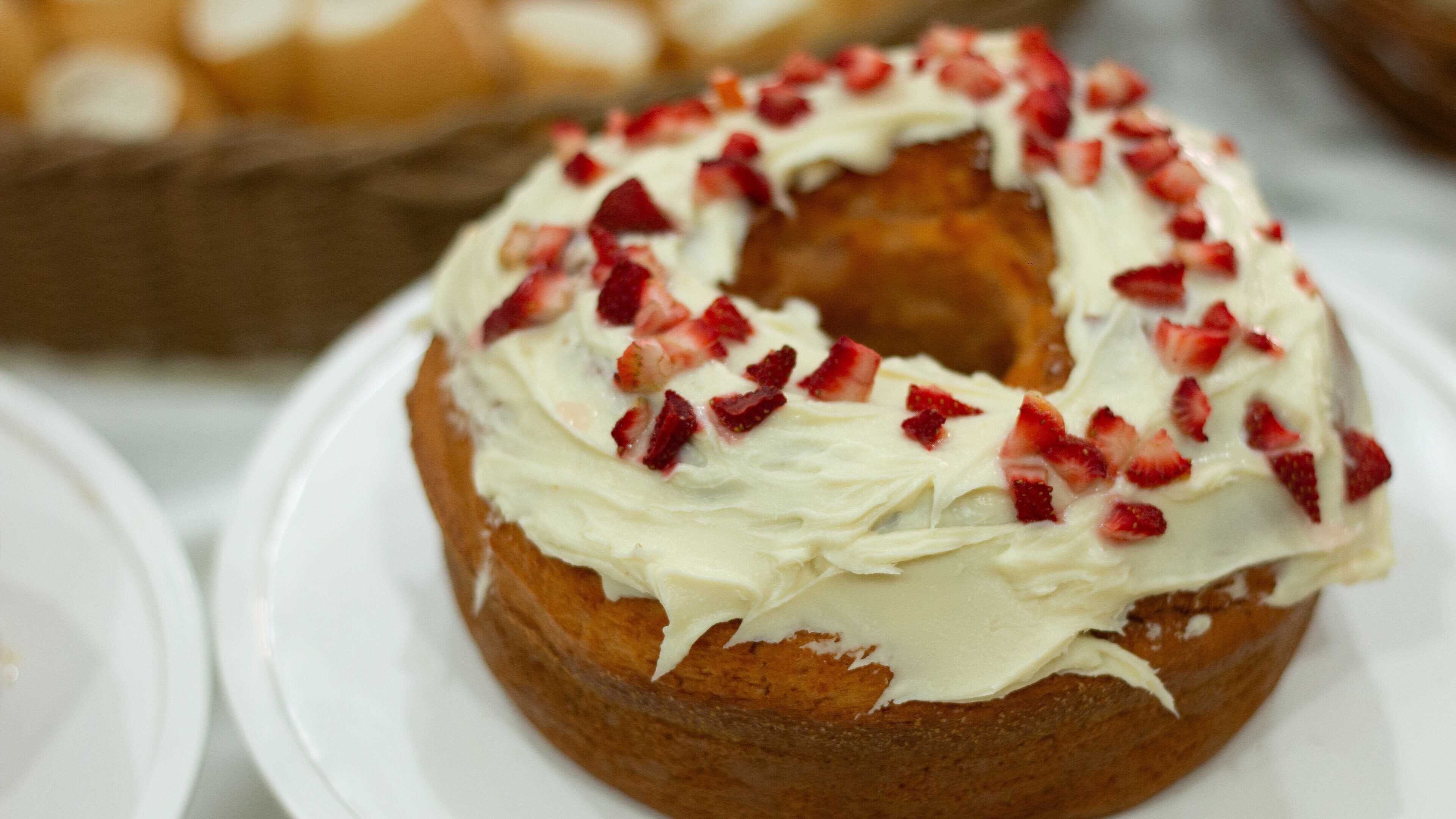 A close-up of a cake with white frosting and strawberry pieces on top.