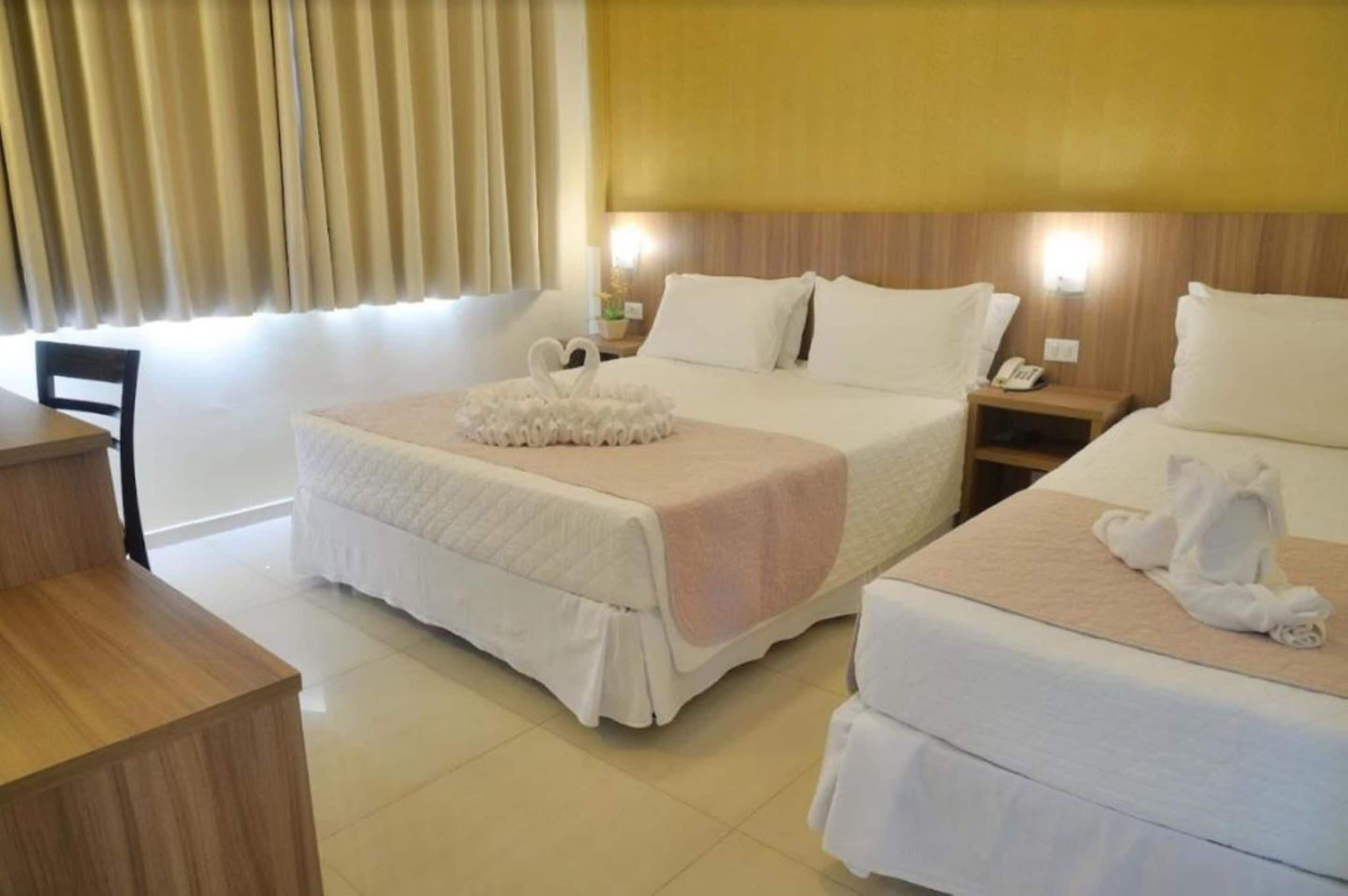 Une chambre d’hôtel avec deux lits, un bureau et une chaise.