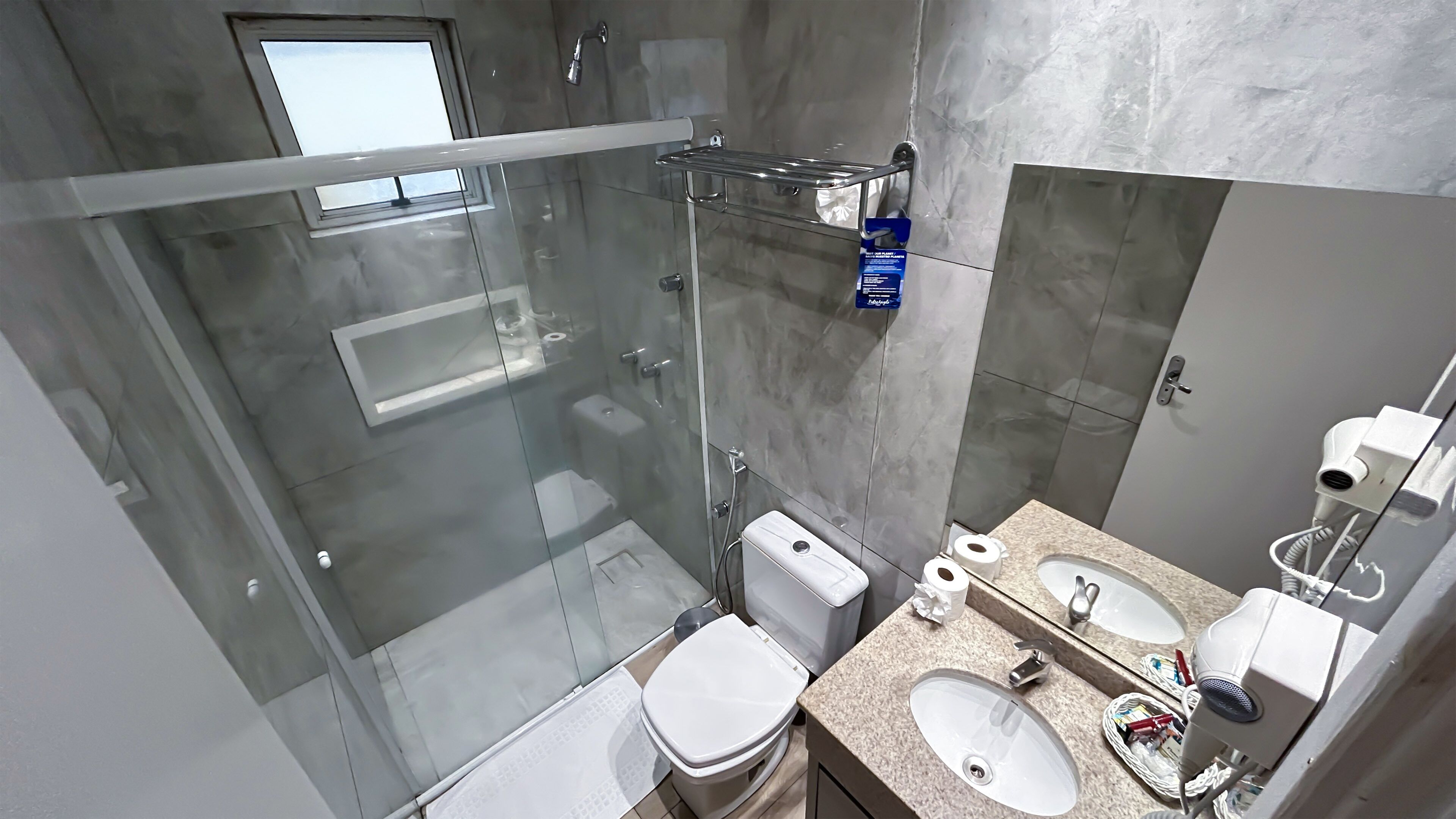 Een moderne badkamer met een glazen douchecabine, toilet, wastafel en spiegel.