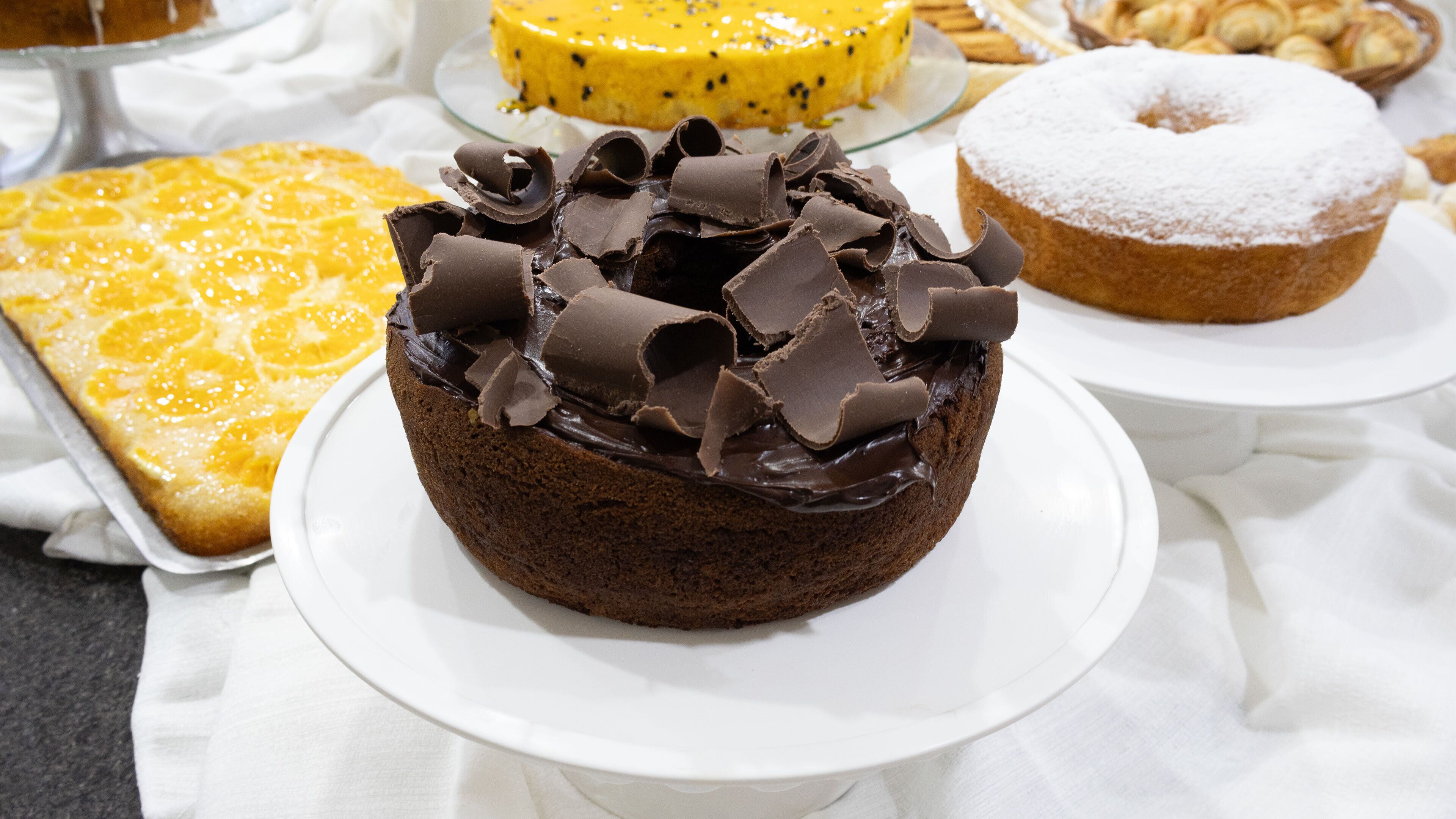 A variety of desserts on white plates, including a chocolate cake with chocolate shavings on top.