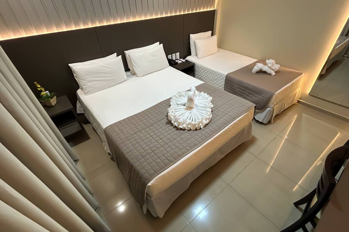 Ein modernes Hotelzimmer mit einem großen Bett, einem kleineren Bett und einer Sitzecke.