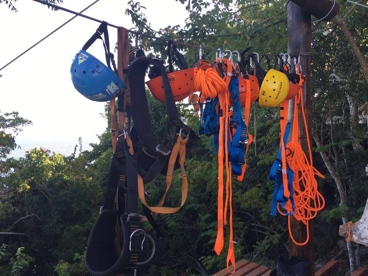 Un tendedero con diverso equipo de escalada, incluyendo cascos y arneses, colgado al aire libre.