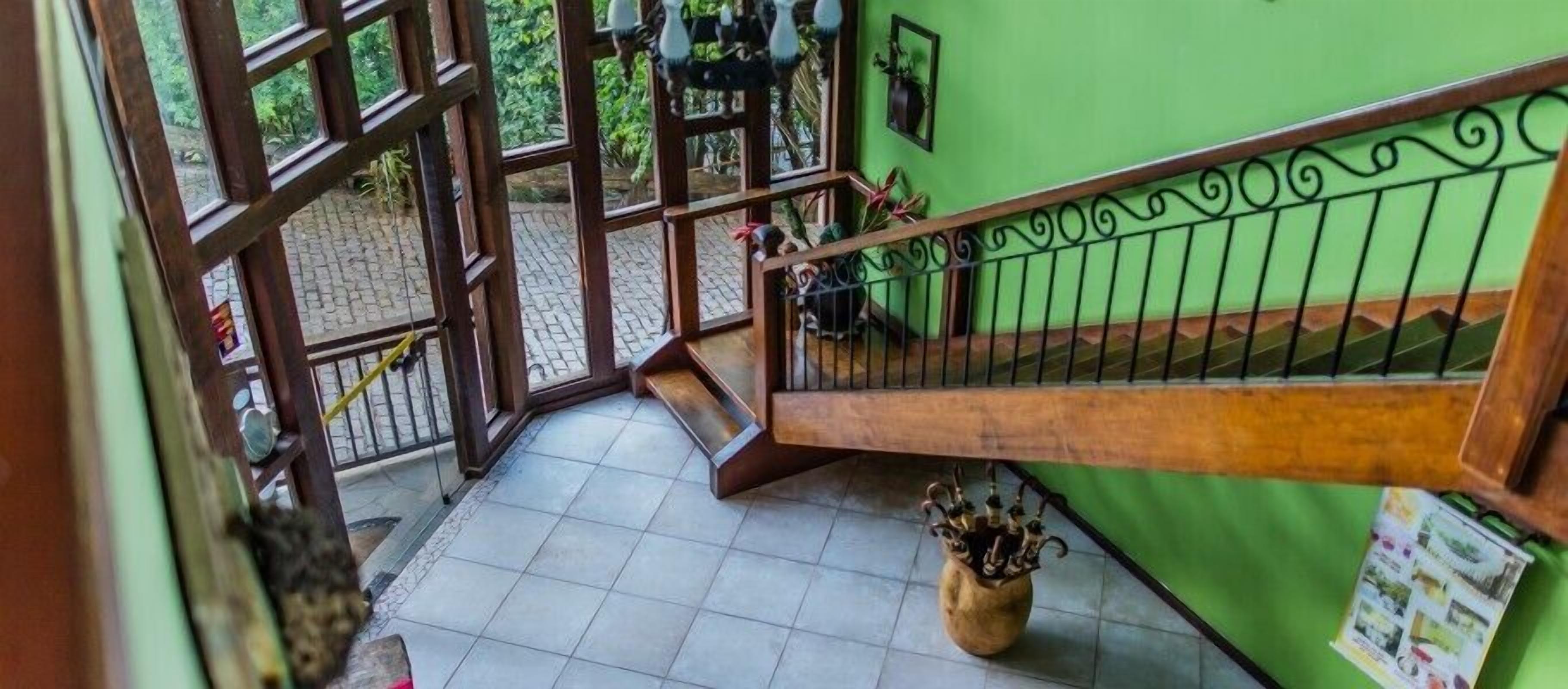 Un escalier avec une rampe en bois et des balustrades en métal, menant à un mur végétal orné d’une affiche.