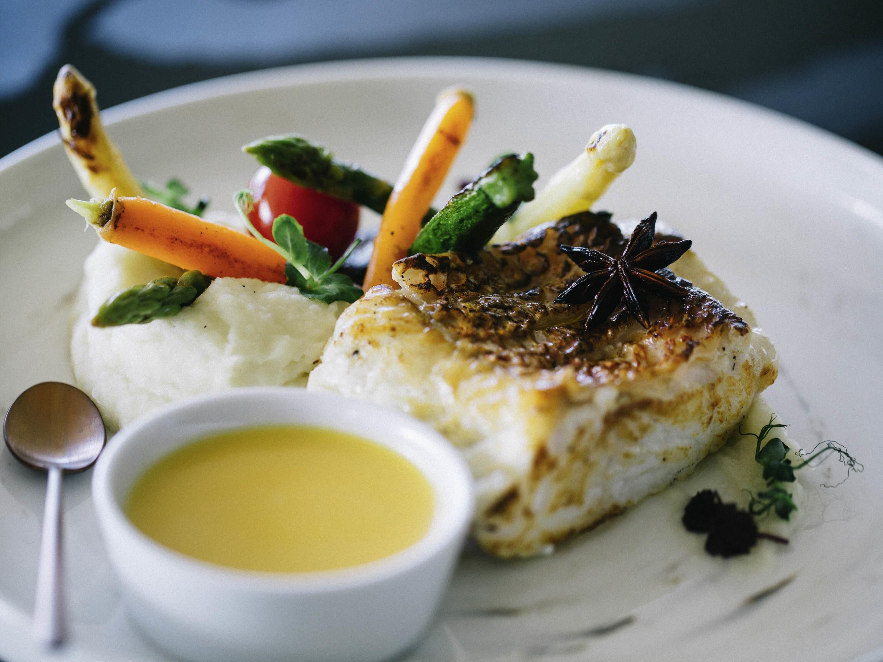 Ein Teller mit Fisch, Kartoffelpüree und Gemüse.