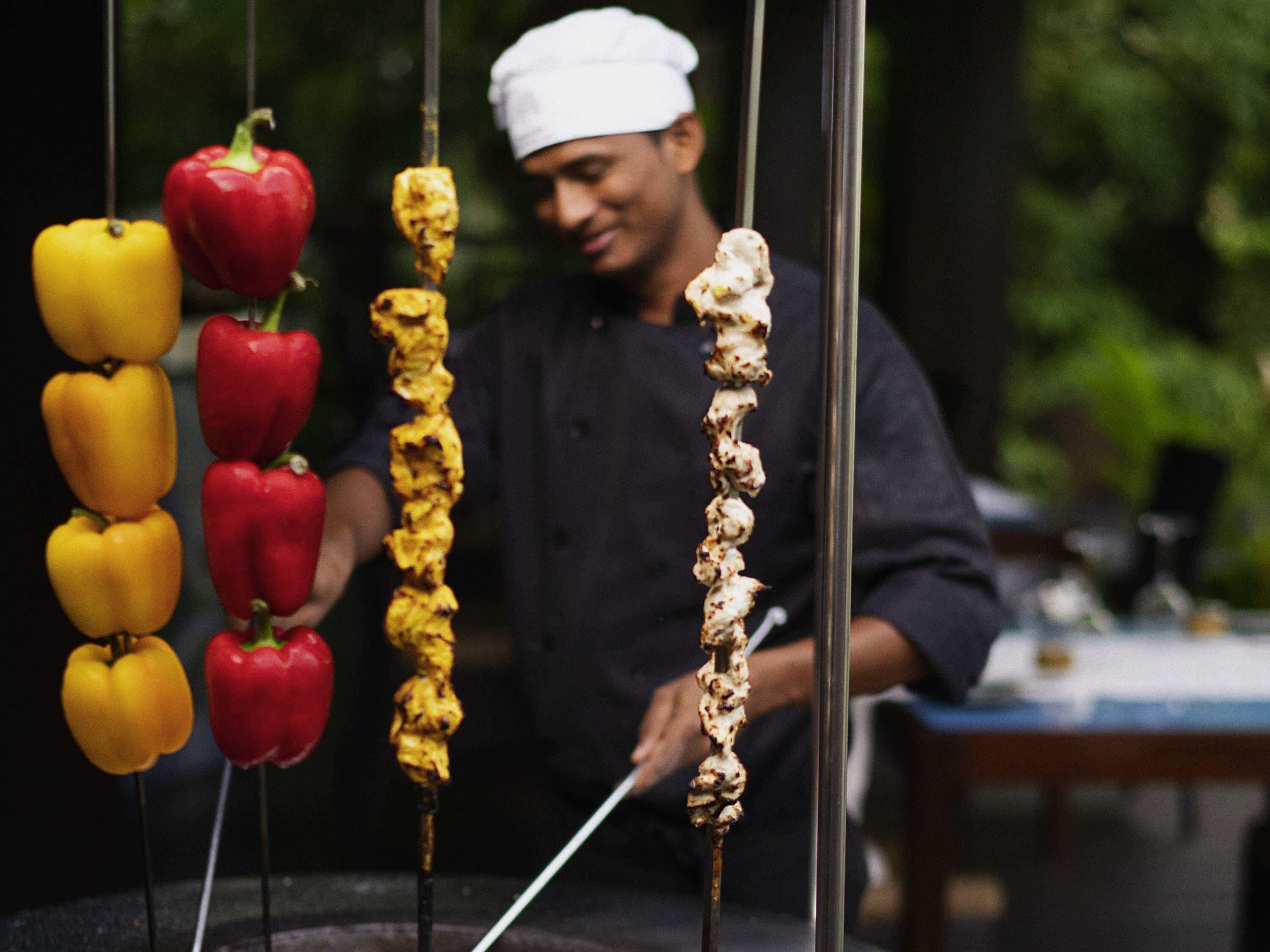 A chef preparing skewers with vegetables and meat.