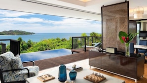 Un salón moderno con vista al mar, una piscina y un comedor con un tablero de ajedrez.