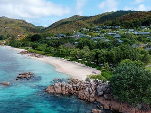 Um resort costeiro com vilas à beira-mar, águas turquesa cristalinas e vegetação exuberante.