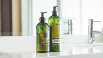Två flaskor lotion står på en hylla i badrummet.