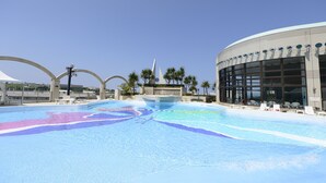 Ein Poolbereich mit einem modernen Gebäude, Palmen und Liegestühlen.
