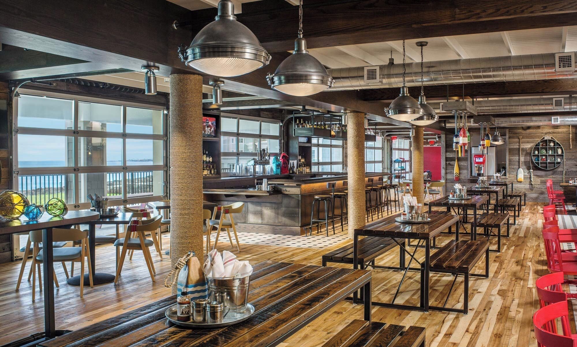 En rummelig restaurant med højt til loftet, synlige ventilationsrør og et barområde.