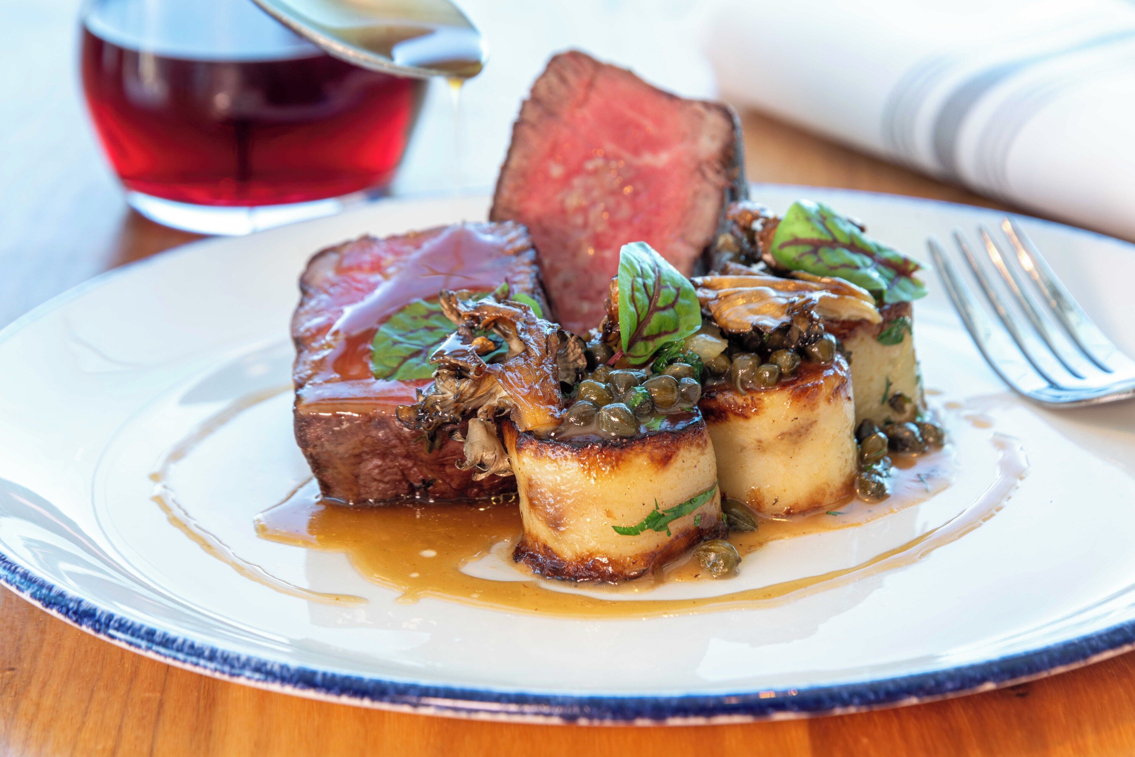 A plate of food with a steak, mushrooms, and a sauce.