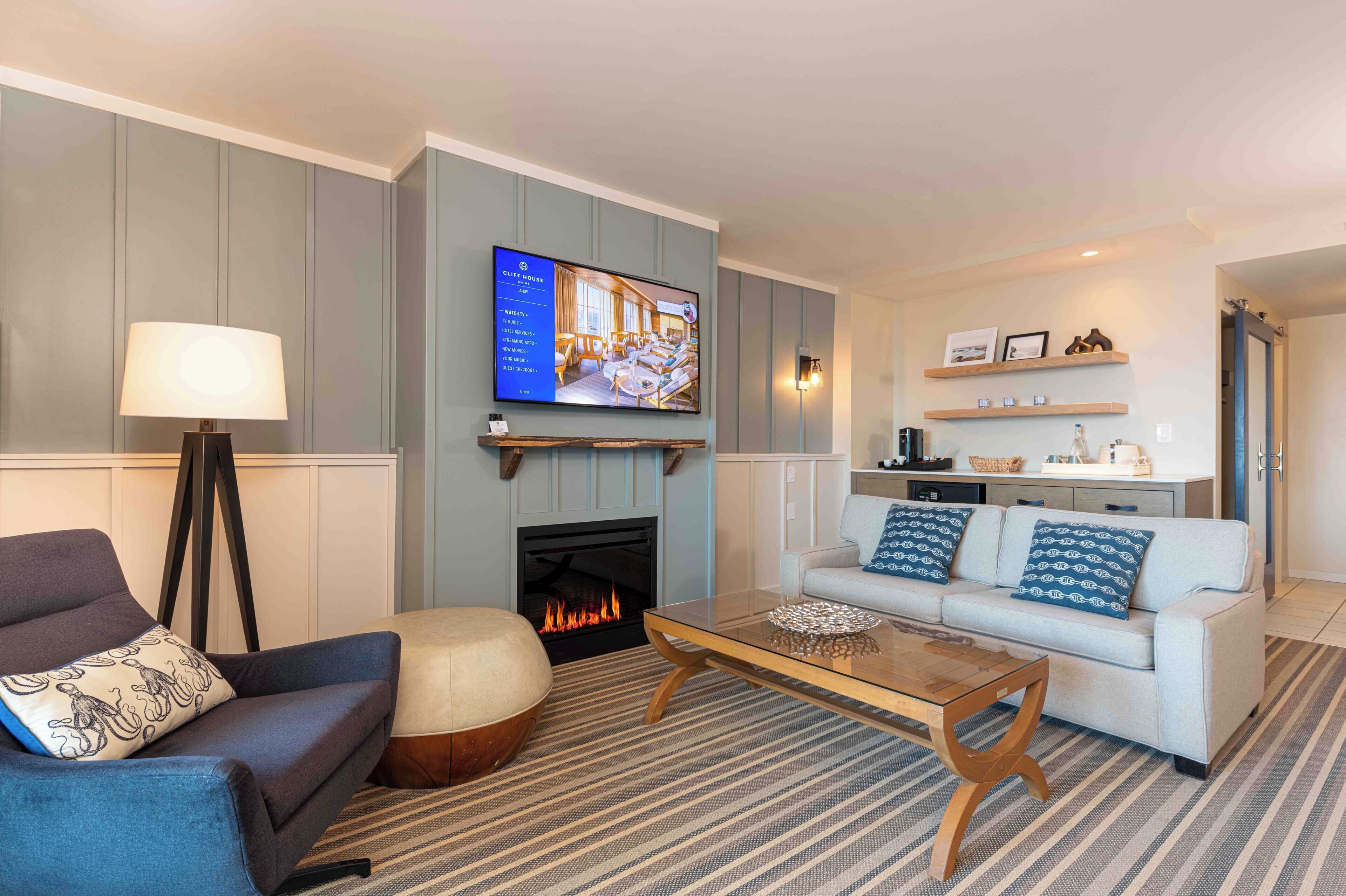 A living room with a fireplace, a sofa, a coffee table, and a television mounted above the fireplace.