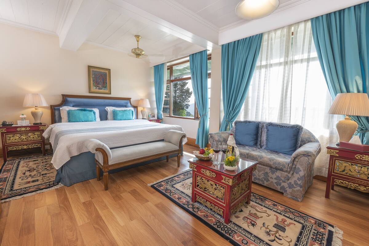 A well-appointed bedroom with a large bed, a sofa, and a small table with a lamp.