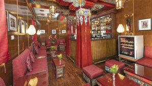 A bar area with red seating, wooden decor, and a television. - The Elgin Nor-Khill - A Heritage Hotel & Spa (Gangtok)